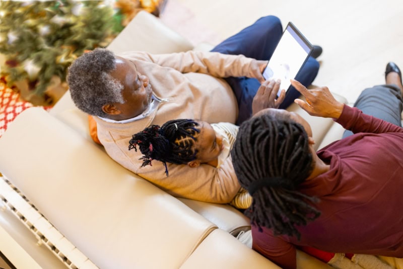 Grandparents and granddaughter on couch looking for furnace repair in Akron, on their laptop.